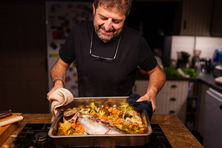 Ein Mann kocht Fisch und Gemüse nach Wikinger-Diät im Ofen