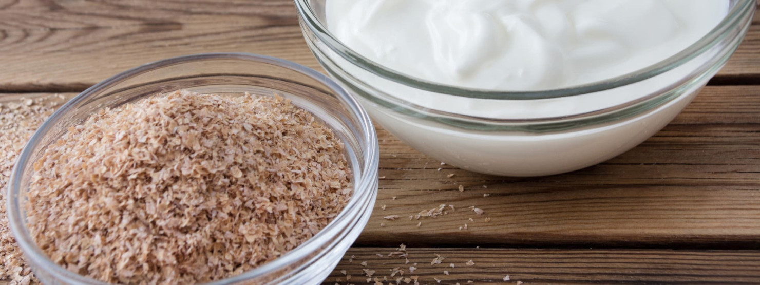 Eine Schlüssel Kleie steht neben einer Schüssel Joghurt