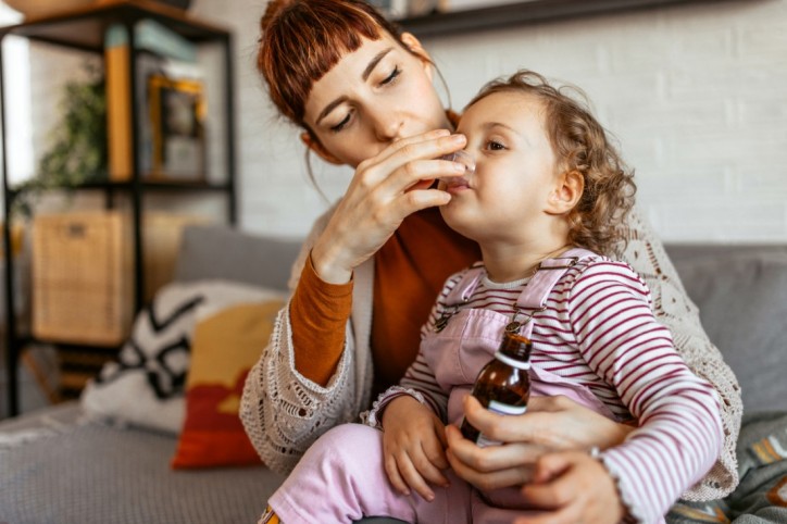Eine Mutter behandelt ihre Tochter mit Drei-Tage-Fieber mit Medikamenten