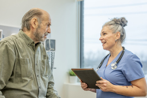 Ein etwa 70-jähriger Mann wir von einer Ärztin in der Praxis zu seiner Gesundheit beraten.