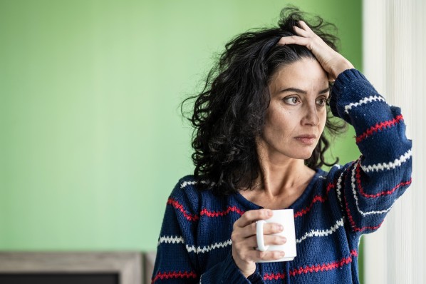 Frau schaut besorgt aus dem fenster