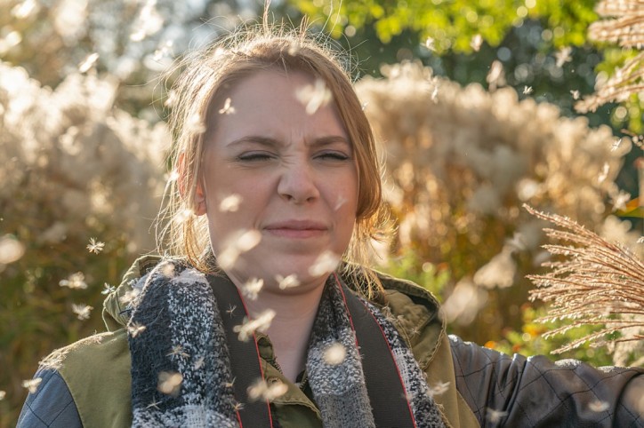 Eine junge Frau mit Heuschnupfen ist Gräserpollen ausgesetzt.