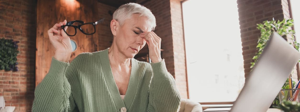 Ältere Frau mit Grauem Star sitzt am Laptop