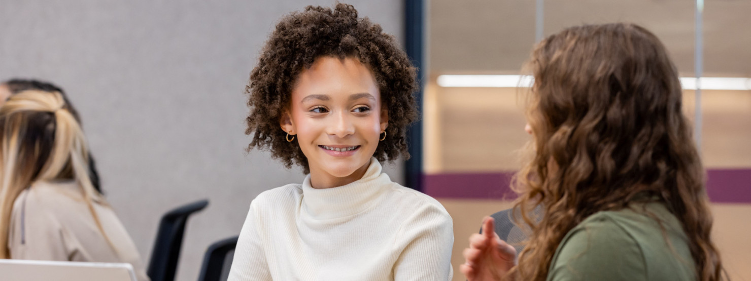 Ein Mädchen, was gegen Meningokokken ACWY geimpft ist, spricht mit einer anderen Jugendlichen.