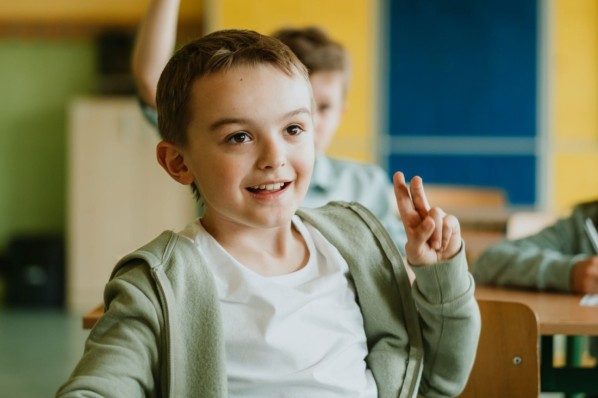 Ein Vater hilft seinem etwa 10 jährigen Sohn bei Aufgaben am Ipad. Der Junge macht sich Notizen auf einem Block.