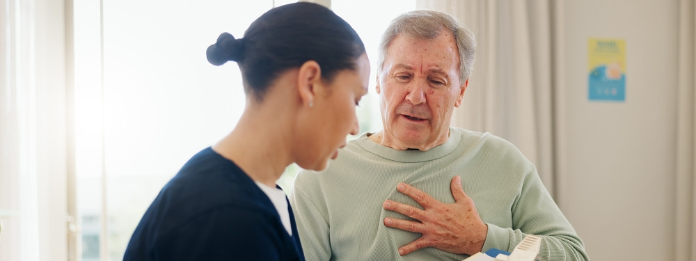 Ein Patient spricht mit einer Arzthelferin der Chest Pain unit in Schönebeck. Er fässt sich dabei an die linke Brust. Die Arzthelferin notiert sich die Symptome eines Herzinfarkts. 