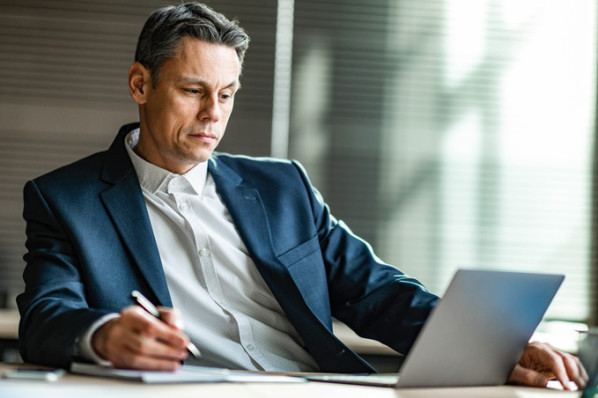 Ein Chef prüft am Laptop die Abwesenheitszeiten seiner Mitarbeiter.
