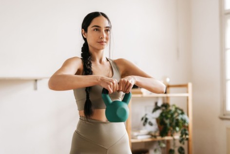 Junge Frau trainiert mit einer Kettlebell.