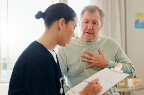 Ein Patient spricht mit einer Arzthelferin der Chest Pain unit in Schönebeck. Er fässt sich dabei an die linke Brust. Die Arzthelferin notiert sich die Symptome eines Herzinfarkts. 