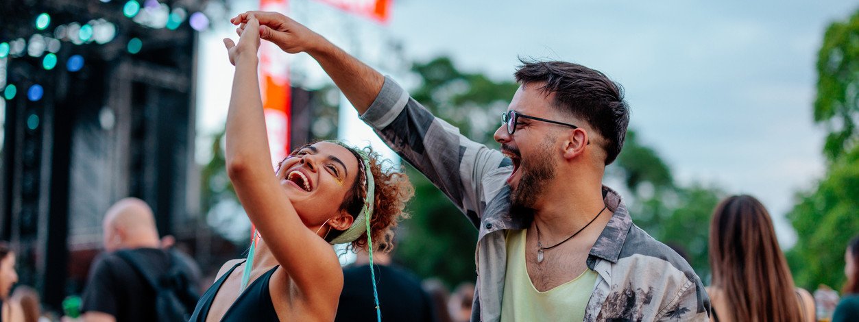 Ein junges Pärchen sitzt vor ihrem Zelt auf einem Festival- Sie essen eine frische Wassermelone.