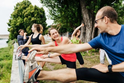 Eine Laufgruppe von fünf Personen dehnt sich vor dem Joggen. 