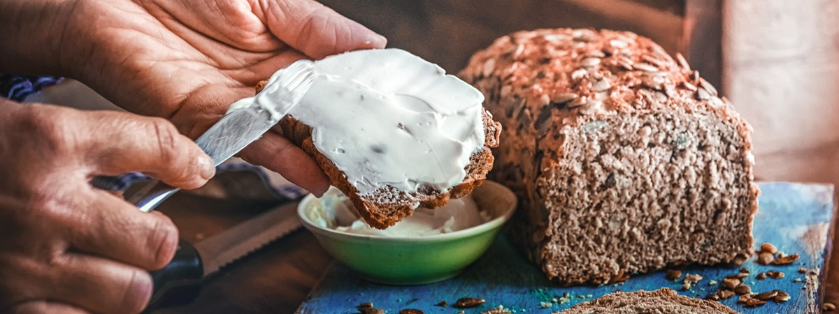 Eine scheibe Vollkornbrot wird mit Quark bestrichen