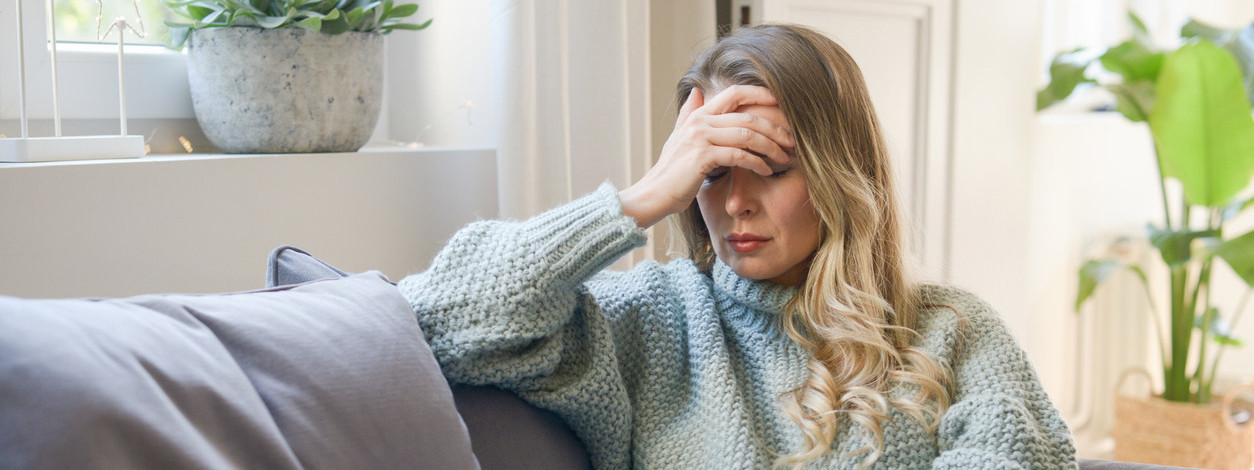 Eine Frau mit Winterdepression sitzt auf dem Sofa
