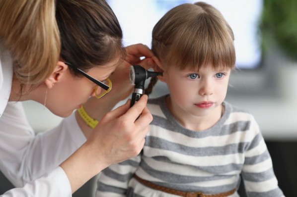 Ein etwa 3 jähriges Mädchen wird von einer HNO-Ärztin mit Hilfe eines Ohrenspiegel am Ohr untersucht.