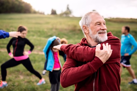 Älterer mann Mitte 60 macht dehnübungen vor einem Workout im Freien