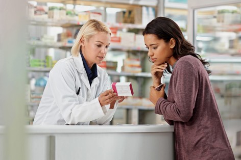 Frau in einer Apotheke lässt zu einem Produkt beraten.