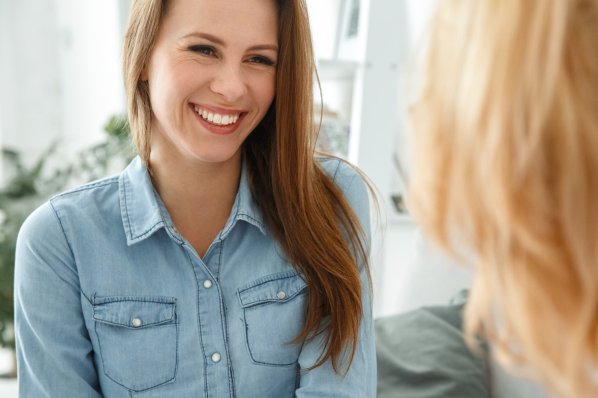 Etwa 30-jährige Frau lächelt in einem Gespräch.