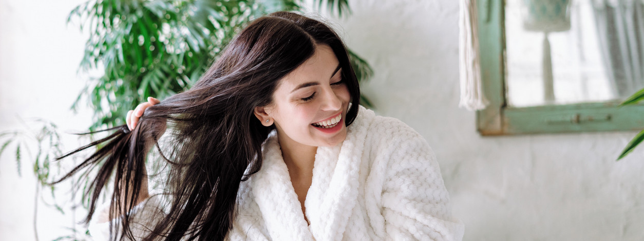 Lächelnde Frau, die den Kopf schüttelt, mit fliegendem Haar, breit lachend und Spaß zu Hause hat