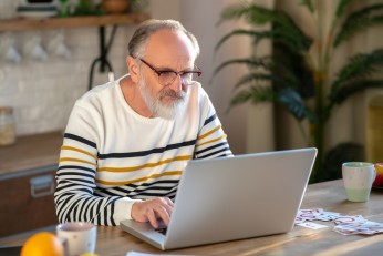Älterer Mann sitzt an einem Laptop