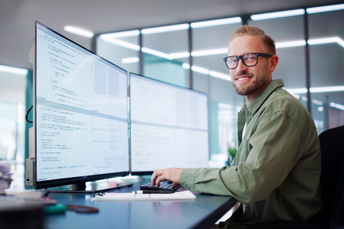 Ein Programmierer sitzt an seinem Schreibtisch und arbeitet an seinem Computer