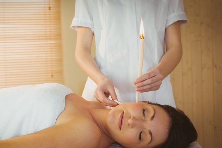 Eine Frau bekommt eine Wellnessanwendung mit einer Ohrenkerze.