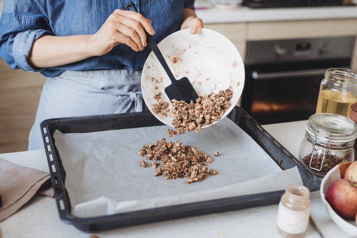 Eine Person schüttet eine Nussmischung auf ein Backblech.