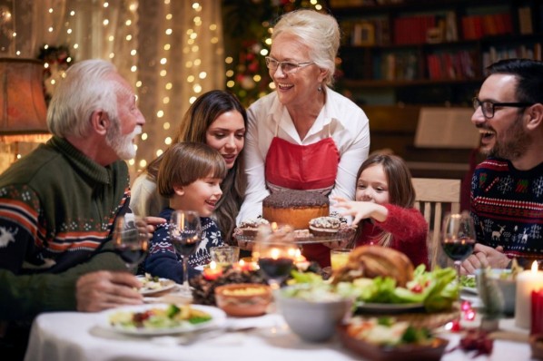 Happy senior woman serving dessert to her family during New Year's Eve in dining room.