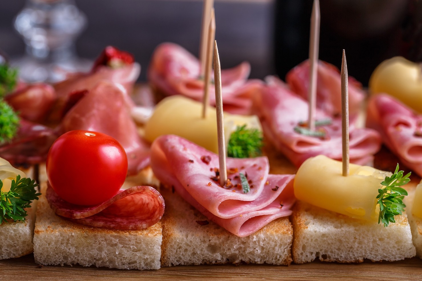 Kleine Schnittchen mit Wurst, Käse und Tomate garniert mit Petersilie