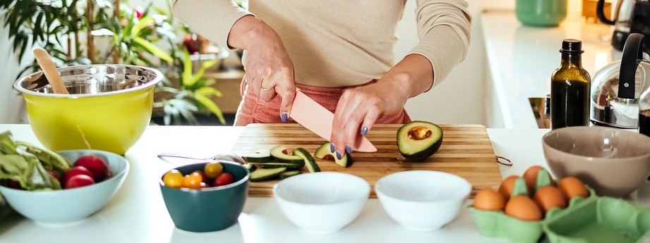 Eine etwa 50-jährige Frau schneidet in der Küche eine Avocado auf.