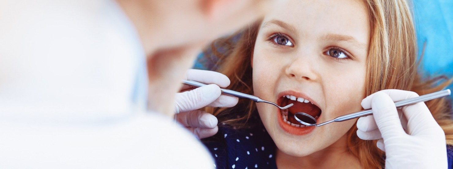 Ein Zahnarzt untersucht die Zähne eines Mädchens.