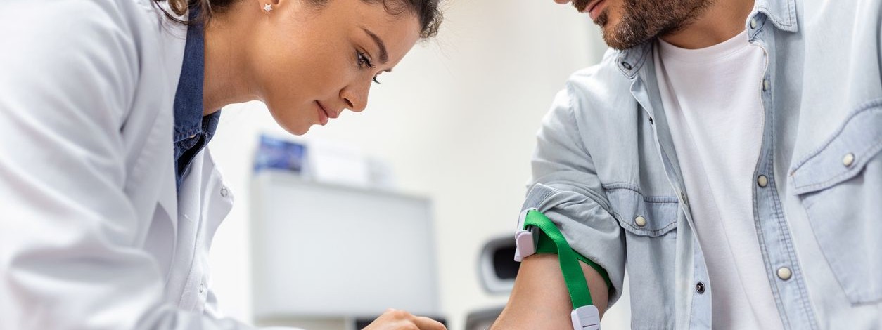 Junger Mann bekommt von seiner Ärztin Blut abgenommen.