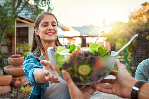 Eine Schale mit gemischtem Salt wird für eine gesunde Grillparty überreicht