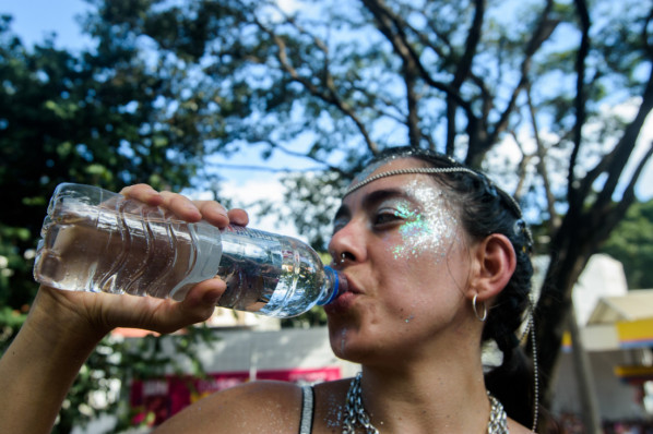 Junge Frau trinkt auf dem Festival aus einer Wasserflasche