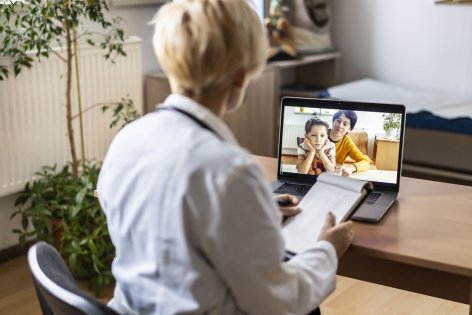 Eine Frau hält ein Tablet in der Hand. Auf dem Bildschirm ist ein Arzt zu sehen, der die Frau berät.