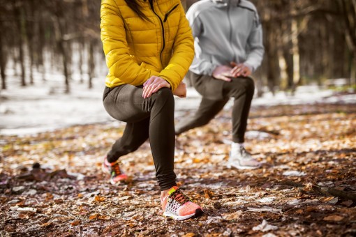 zwei personen in sportkleidung machen dehnübungen im Wald