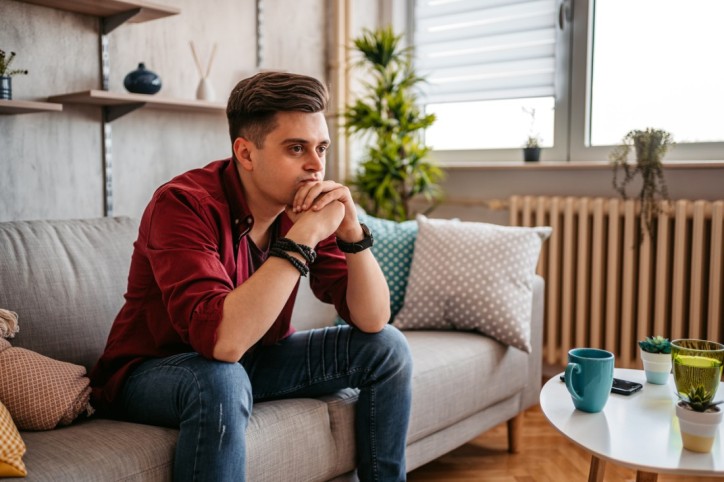 Ein Mann mit Gesichtsblindheit sitzt nachdenklich auf einem Sofa.