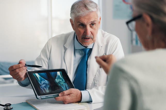 Ein Arzt bespricht das Ergebnis einer Knochendichtemessung mit einer Patientin