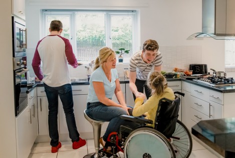 Familie einer Rollstuhlfahrerin in der Küche