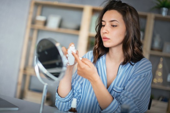 Young woman applying anti-pimple cream.