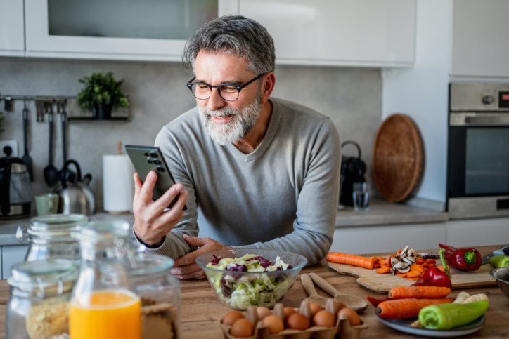 Ein Mann notiert sich in seinem Smartphone seine Lebensmittel für seine Ernährungsumstellung.