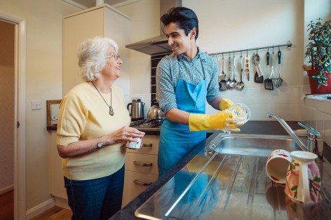 Mann hilft Seniorin beim Spülen