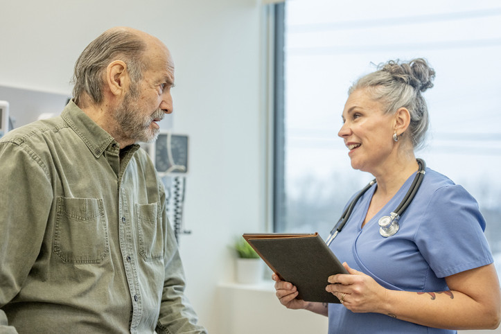 Ein etwa 70-jähriger Mann wir von einer Ärztin in der Praxis zu seiner Gesundheit beraten.