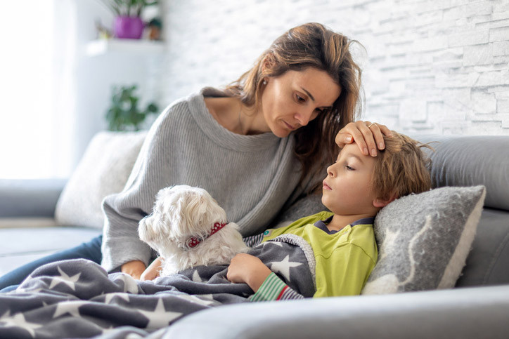 Ein kleiner junger mit Pseudokrupp wird von seiner Mutter versorgt