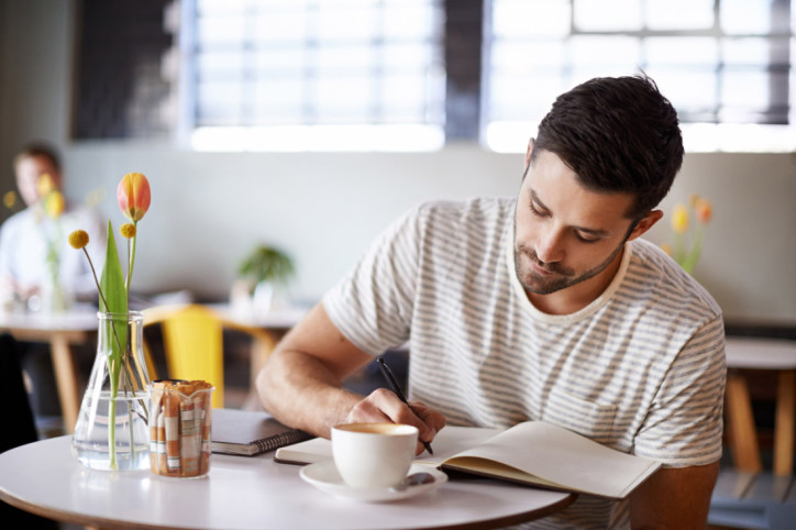 Ein Mann führt ein Dankbarkeitsjournal in einem Café