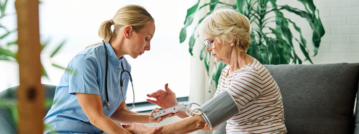 Eine Pflegefachkraft führt eine geriatrische Behandlung bei einer Seniorin durch