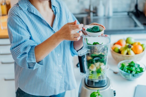 Eine Person gibt Spirulina in einen Mixer.