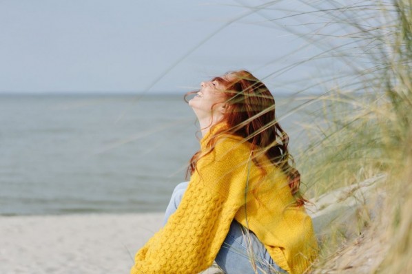 Junge Frau sitzt am Strand und genießt die Sonne. 