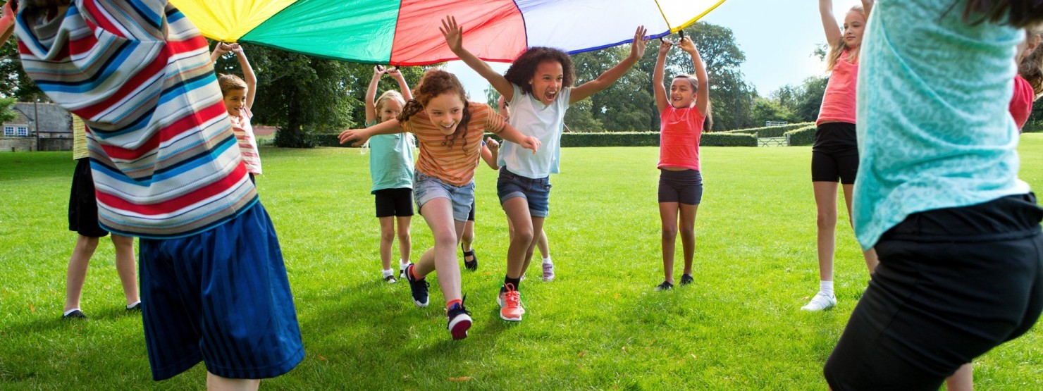 Kindergruppe spielt mit einem bunten Fallschirmtuch.