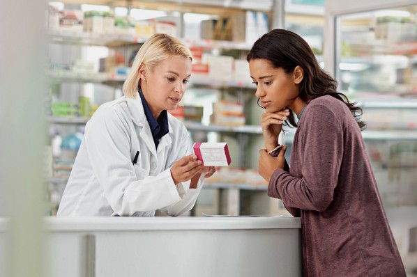 Eine Apothekerin berät eine junge Frau zur Einnahme ihrer Antibiotika. 