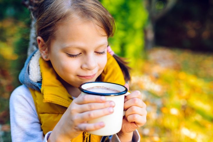 Ein kleines Mädchen trinkt Kakao aus einer Tasse